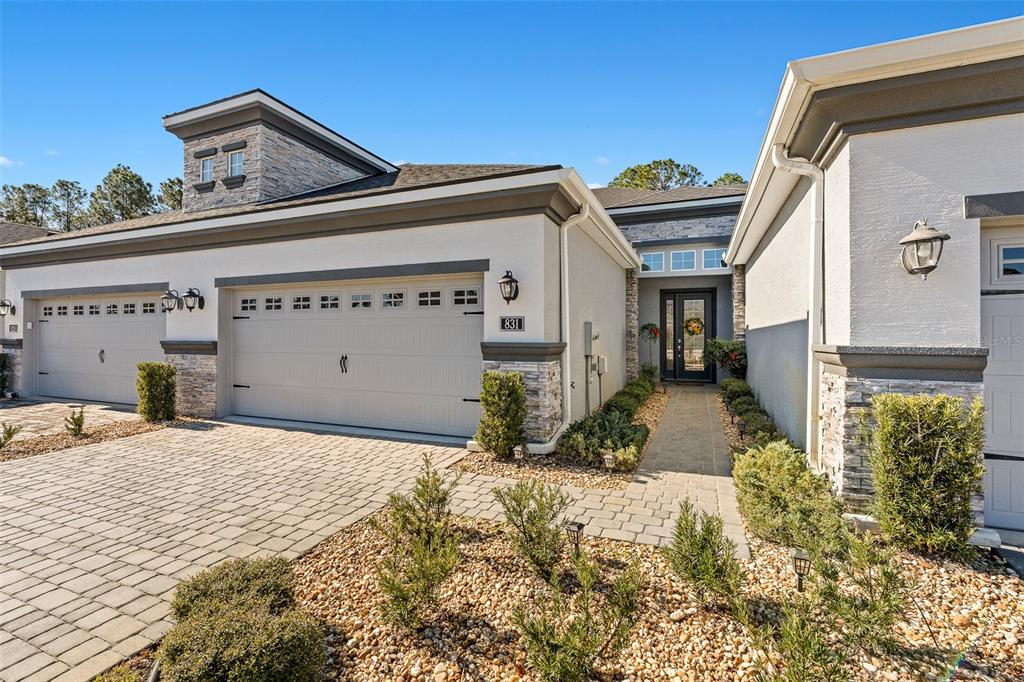The exterior of a modern house features a paved driveway, two garage doors, and stone accents — 831 PINEWOOD DRIVE, ORMOND BEACH, FL