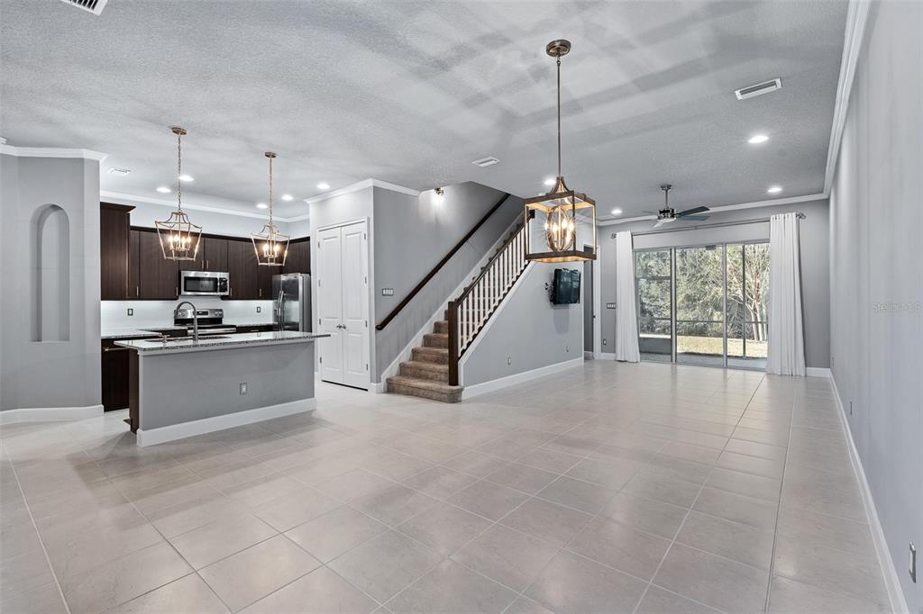 An open-concept kitchen and living area features dark wood cabinets, granite countertops, and stairs — 831 PINEWOOD DRIVE, ORMOND BEACH, FL