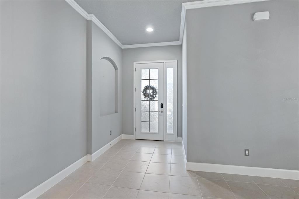 An entryway features light gray walls, tile flooring, a recessed wall niche, and a glass-paneled door — 831 PINEWOOD DRIVE, ORMOND BEACH, FL
