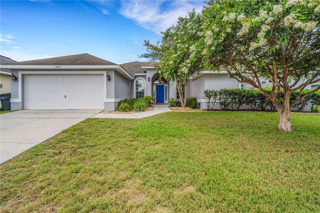 A concrete walkway leads to the blue front door of a gray stucco house — 8722 FORT SOCRUM VILLAGE PLACE, LAKELAND, FL
