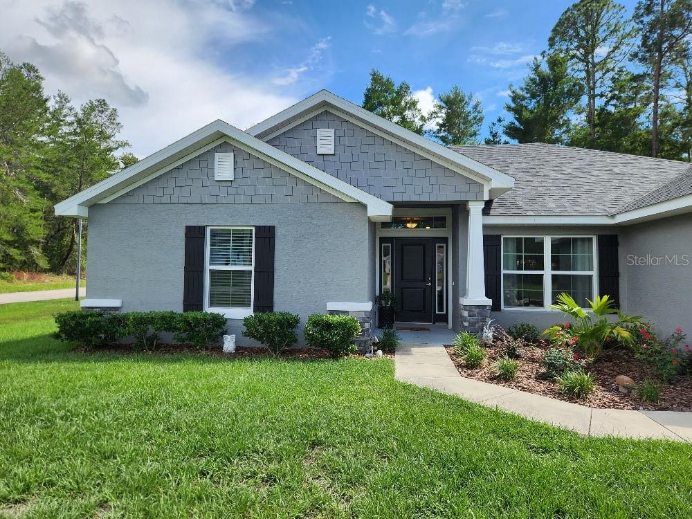 The exterior of a house features a gray front door, stone pillars, and shingled siding — 47 VILLAGE CENTER DRIVE, HOMOSASSA, FL