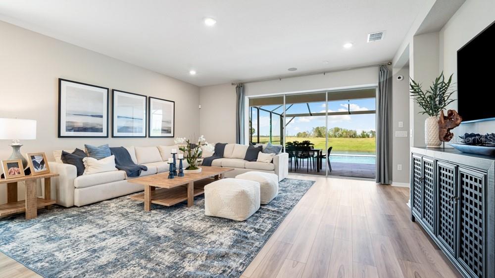 A modern kitchen with white cabinets, stainless steel appliances, and an island overlooks a living area — 12817 DOCKYARD TRAIL, PALMETTO, FL