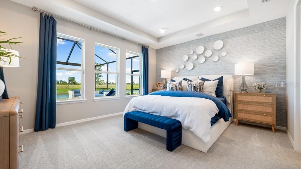A modern kitchen features white cabinets, a quartz island with bar stools, and stainless appliances — 12817 DOCKYARD TRAIL, PALMETTO, FL