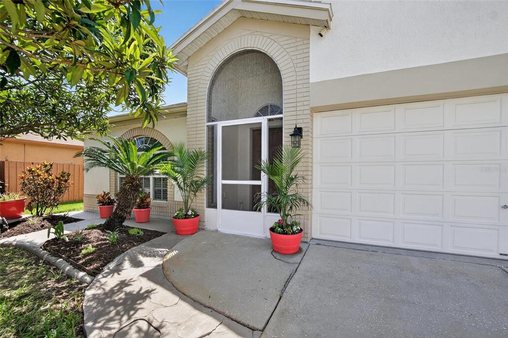 A front exterior view of a house with a garage, arched entryway, and potted plants — 13029 PRESTWICK DRIVE, RIVERVIEW, FL