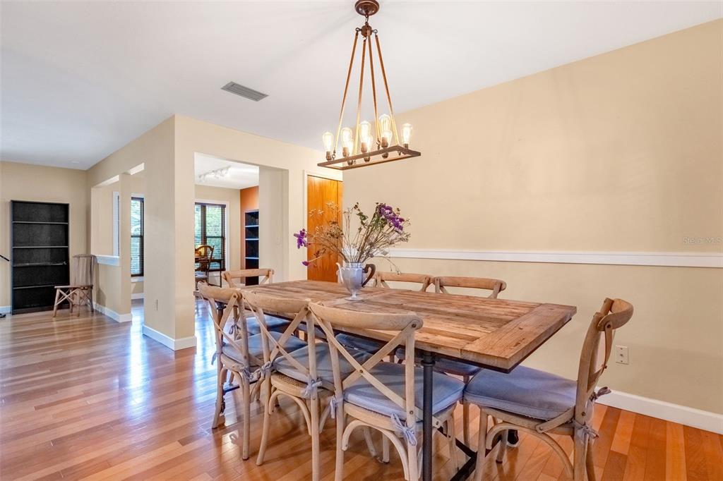 A dining room features a rustic wooden table, cross-back chairs, and a modern linear chandelier — 1850 BRYAN AVENUE, WINTER PARK, FL