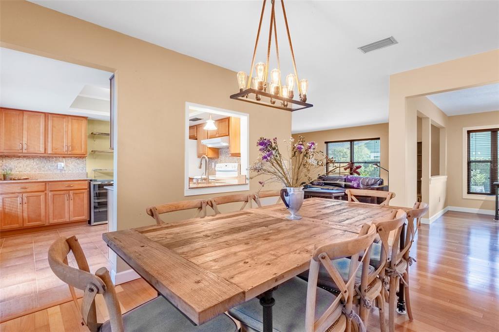 A dining room with a rustic wooden table, farmhouse chairs, and a modern rectangular chandelier — 1850 BRYAN AVENUE, WINTER PARK, FL