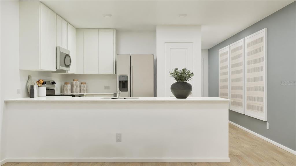 A modern kitchen features white cabinetry, stainless steel appliances, and a white breakfast bar — 3950 AMERS LOOP, HAINES CITY, FL