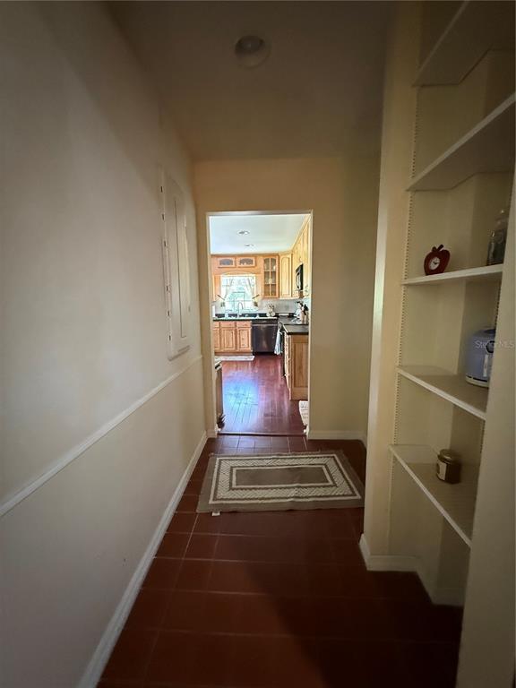 A hallway with tile flooring and built-in shelving leads to a kitchen with wooden cabinets — 305 WHITE OAK DRIVE, ALTAMONTE SPRINGS, FL