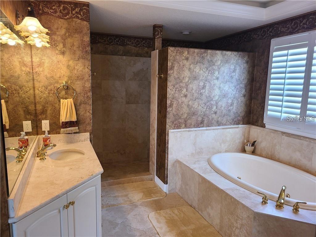 A bathroom features a tiled soaking tub, a walk-in shower, and a vanity with wallpaper — 8149 VIA ROSA, ORLANDO, FL