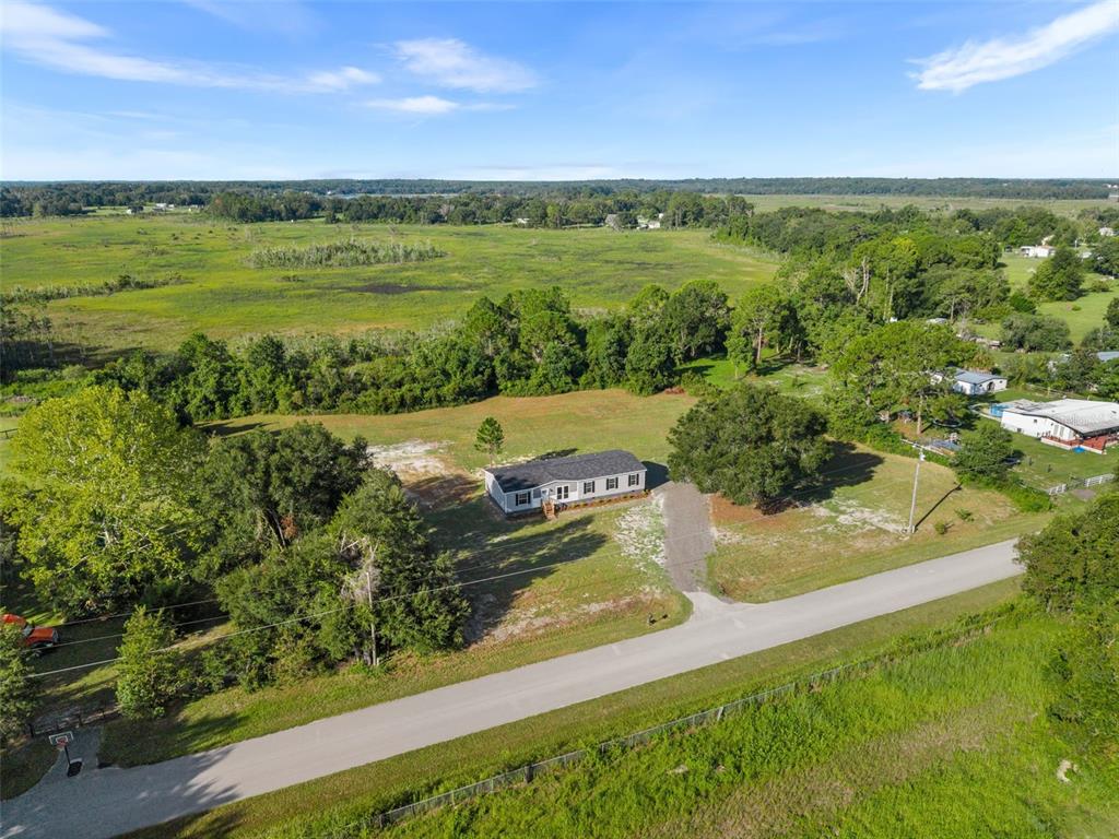 An aerial view shows a single-story house situated on a large, grassy rural lot — 12610 SE 115 STREET, OCKLAWAHA, FL