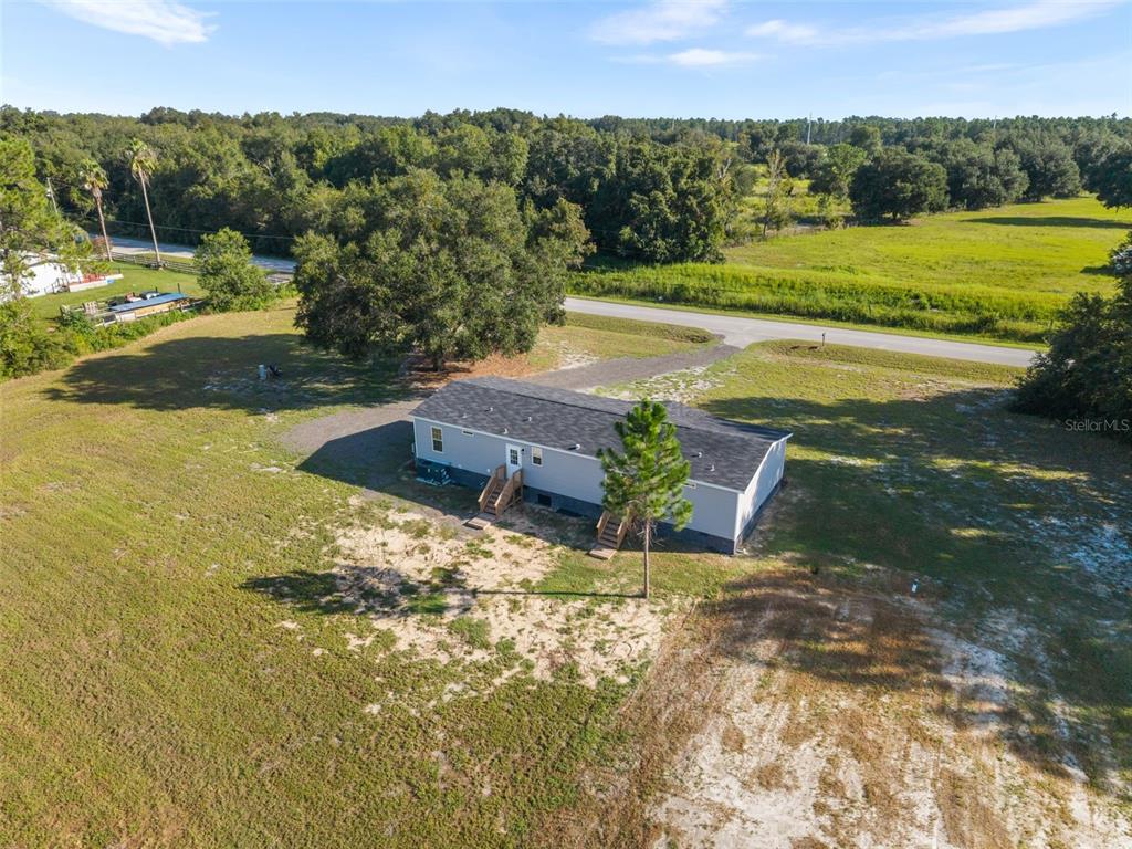 An aerial view shows a single-story house with a dark roof on a large grassy lot — 12610 SE 115 STREET, OCKLAWAHA, FL