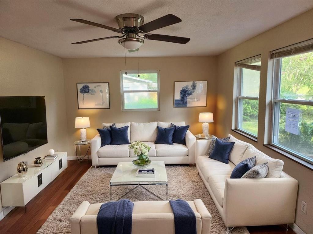 This living room features white sofas, a glass coffee table, and a ceiling fan — 2861 SE 18TH AVENUE, GAINESVILLE, FL