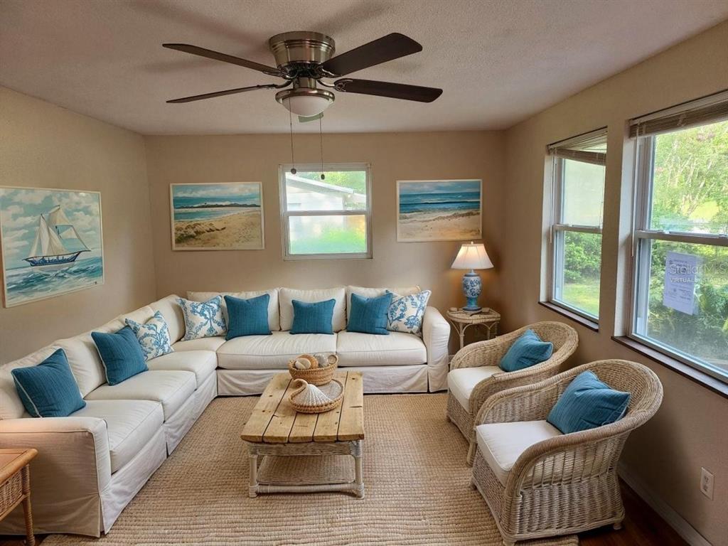 A sunroom features a large white sectional sofa, two wicker chairs, and coastal-themed wall art — 2861 SE 18TH AVENUE, GAINESVILLE, FL