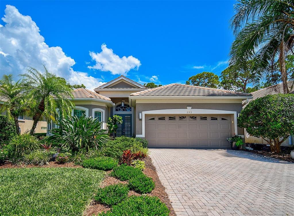 A single-story house with a beige stucco exterior, a tiled roof, and a paved driveway — 293 TURQUOISE LANE, OSPREY, FL