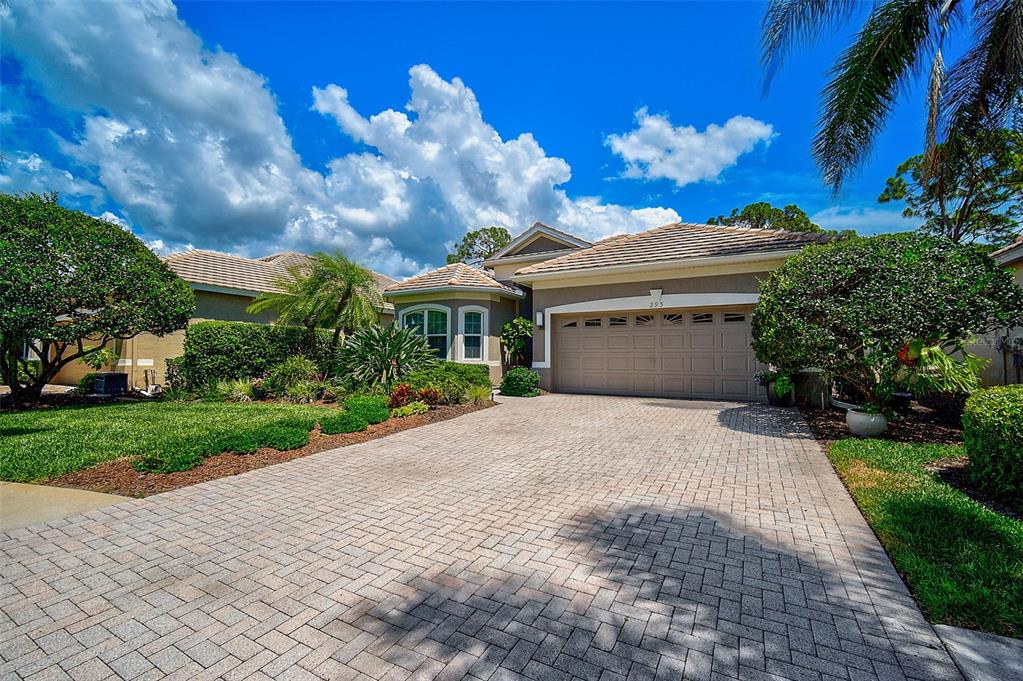 A single-story house with a paved driveway, a two-car garage, and lush landscaping — 293 TURQUOISE LANE, OSPREY, FL