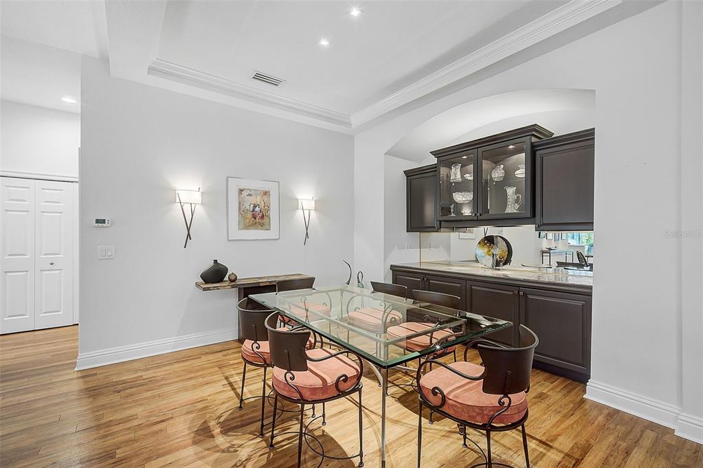 A dining room features a glass-topped table, dark cabinetry, and hardwood flooring — 293 TURQUOISE LANE, OSPREY, FL