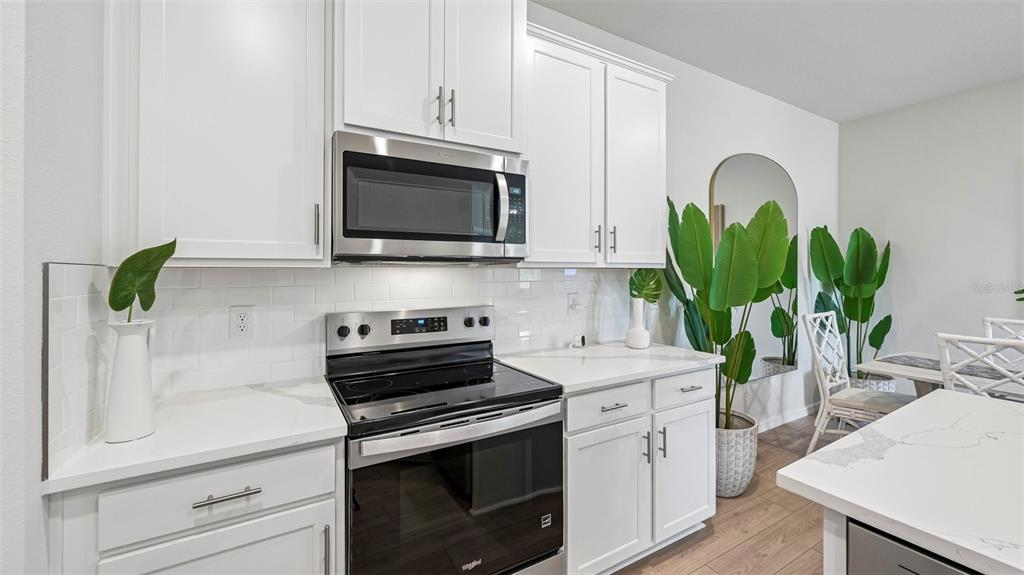 A modern kitchen features white cabinetry, stainless steel appliances, and a white quartz countertop — 15824 8TH PLACE E, BRADENTON, FL