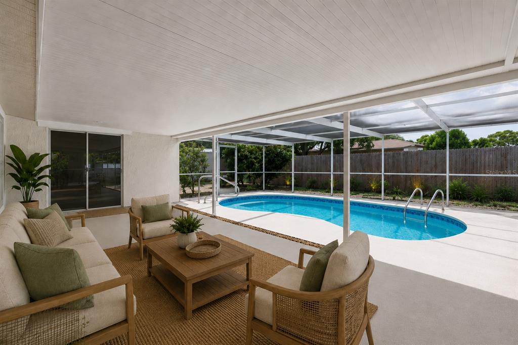 A covered patio features outdoor furniture, a rug, and a screened-in swimming pool — 7604 JASMINE BOULEVARD, PORT RICHEY, FL