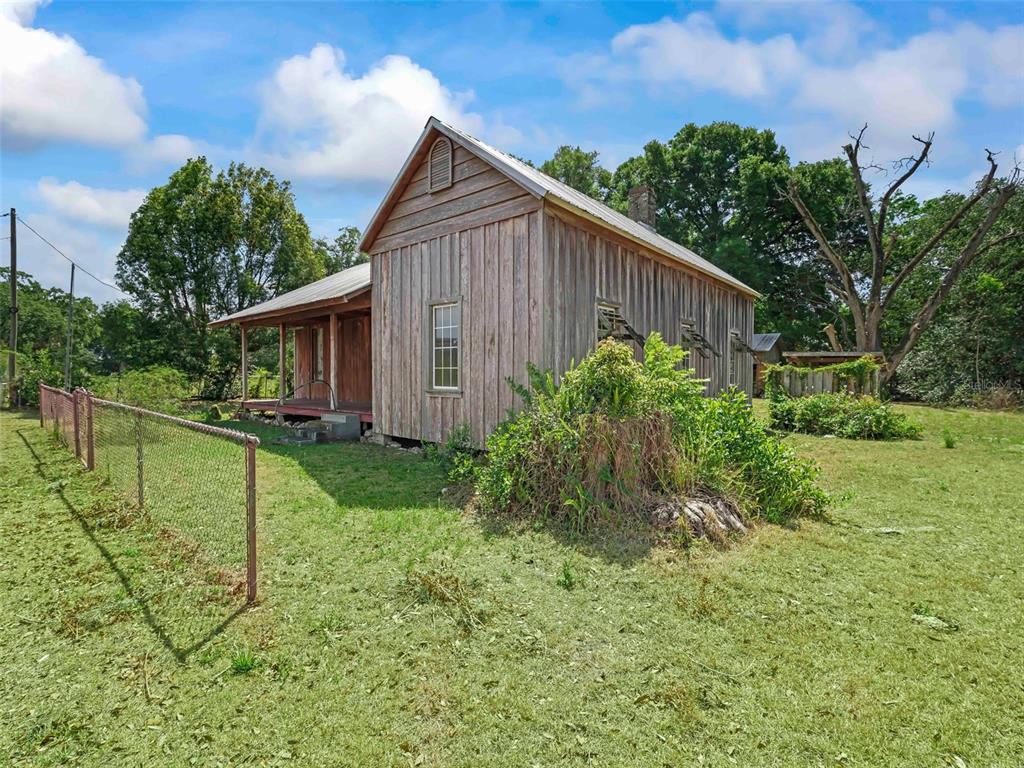 A weathered wooden house with a metal roof and a front porch sits on grass — 4241 COUNTY ROAD 106, OXFORD, FL