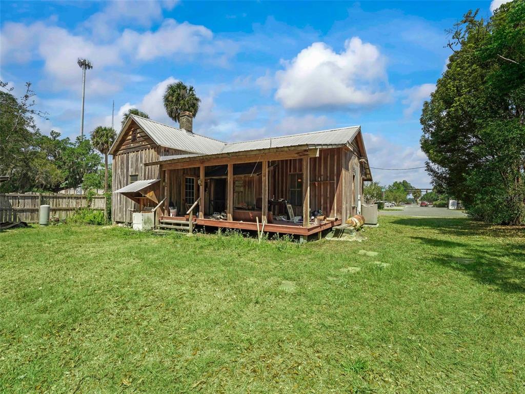 A rustic wooden house with a metal roof and a large front porch sits outdoors — 4241 COUNTY ROAD 106, OXFORD, FL
