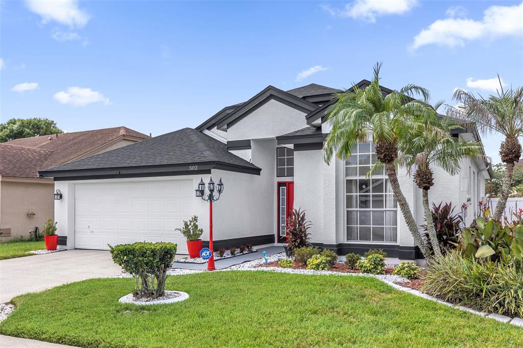 A white single-story house with a dark roof, red front door, and a front lawn — 502 BRIGHTVIEW DRIVE, LAKE MARY, FL