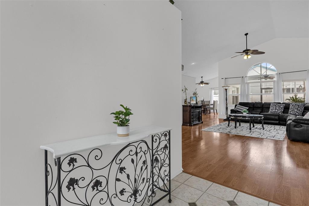 A foyer with a decorative metal console table opens into a living room with hardwood floors — 502 BRIGHTVIEW DRIVE, LAKE MARY, FL
