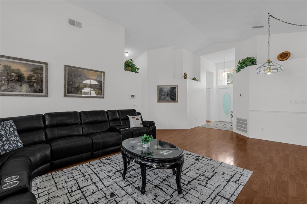 A living room features a black leather sectional, a glass coffee table, and hardwood flooring — 502 BRIGHTVIEW DRIVE, LAKE MARY, FL