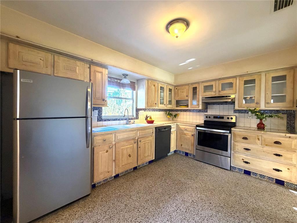 A kitchen features light wood cabinets, stainless steel appliances, tiled countertops, and a speckled floor — 1842 59TH STREET S, GULFPORT, FL