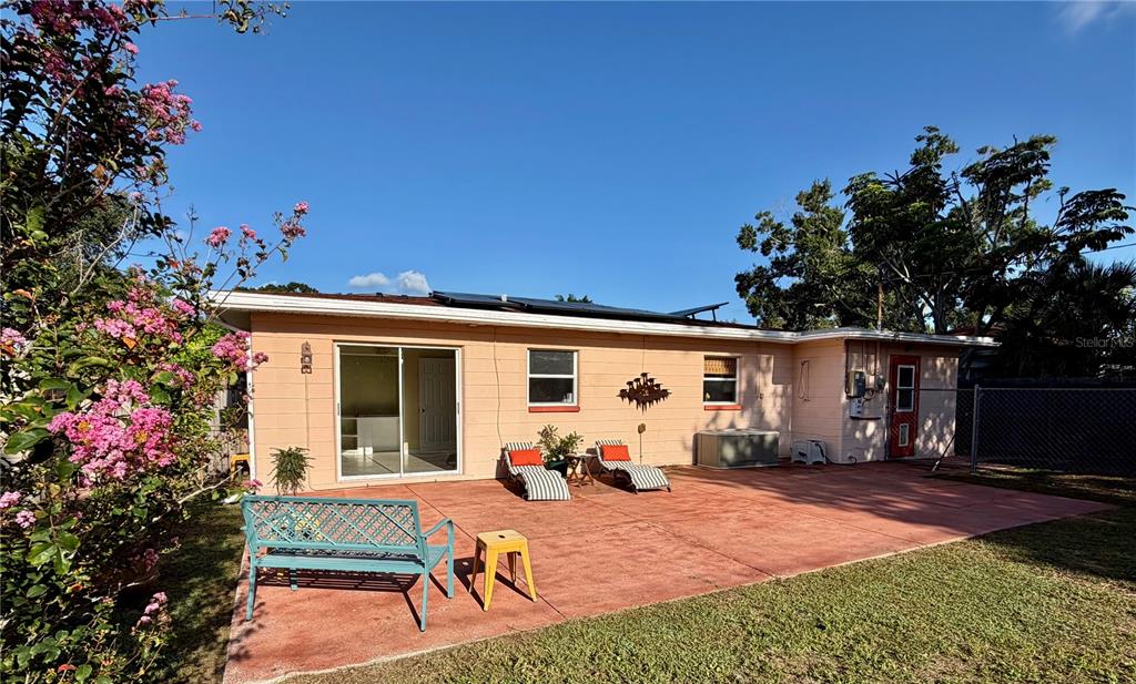 A peach-colored house exterior features a large concrete patio, sliding glass doors, and landscaping — 1842 59TH STREET S, GULFPORT, FL