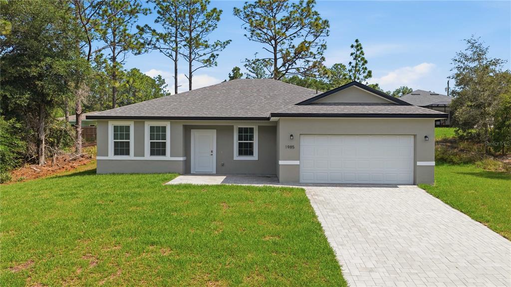 An aerial view shows a single-story house with a gray roof on a grassy lot — 1985 W CORRINE STREET, DUNNELLON, FL