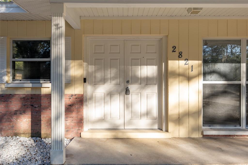 The front entrance features double white doors, a brick base, and a concrete porch — 2821 NE 17TH TER, GAINESVILLE, FL