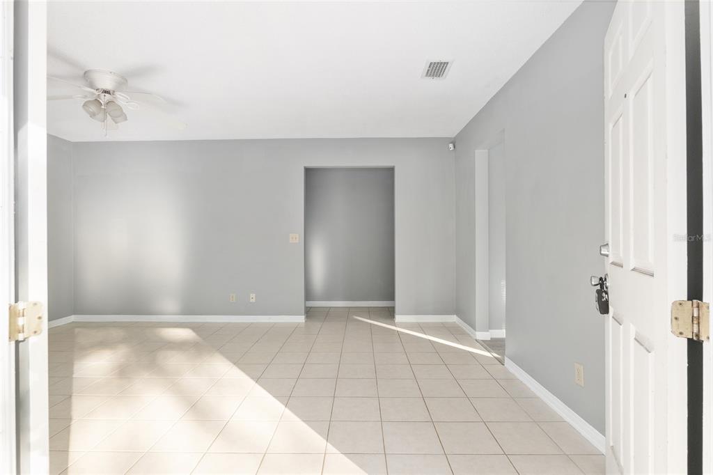 An empty room with light gray walls, tiled flooring, and a ceiling fan — 2821 NE 17TH TER, GAINESVILLE, FL