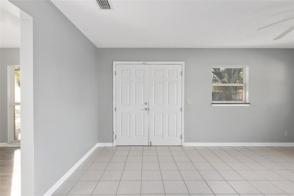 A room with light gray walls, white double entry doors, and light-colored floor tiles — 2821 NE 17TH TER, GAINESVILLE, FL