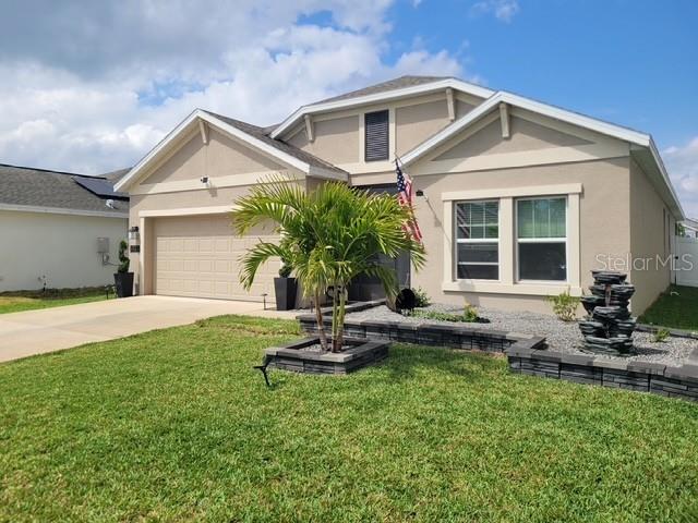 A beige single-story house features a two-car garage, a palm tree, and a stone fountain — 6935 PERCH HAMMOCK LOOP, GROVELAND, FL