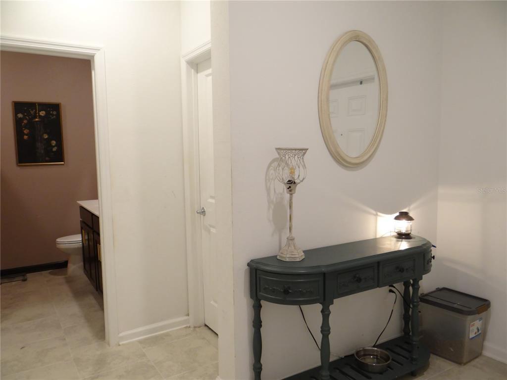 A hallway features a blue console table, a wall mirror, and a doorway to a bathroom — 6935 PERCH HAMMOCK LOOP, GROVELAND, FL