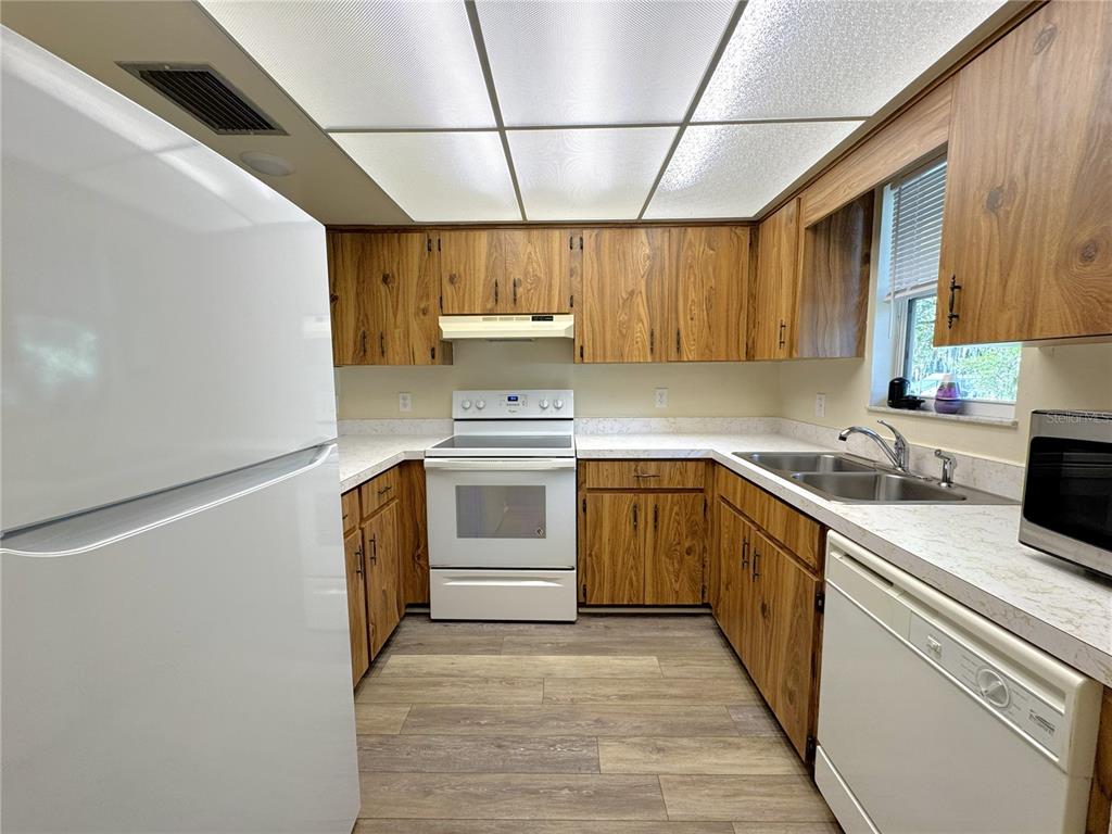 A kitchen features wood cabinets, white appliances, laminate countertops, and a drop ceiling — 6825 E DOWNING STREET UNIT 432, INVERNESS, FL