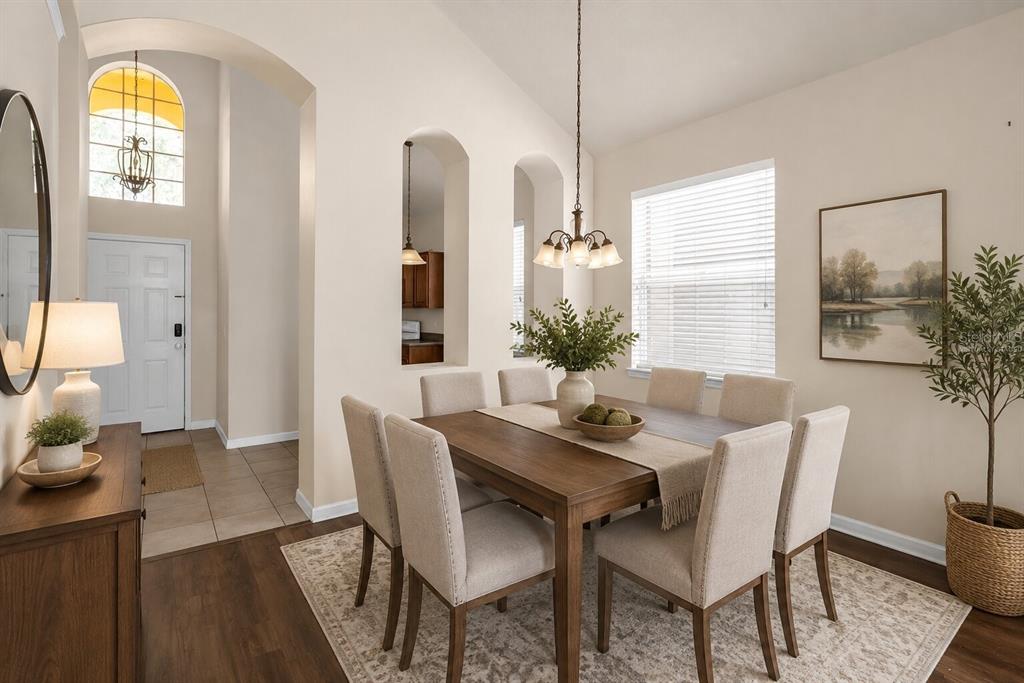 A dining room with a wooden table, upholstered chairs, and arched wall cutouts — 1755 ROYAL RIDGE DRIVE, DAVENPORT, FL