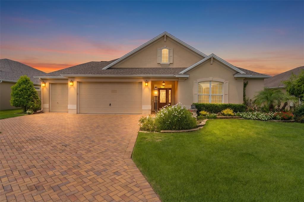 A brick walkway leads to a landscaped garden bed with a lamp post and flowers — 3452 BOSIE RUN, THE VILLAGES, FL
