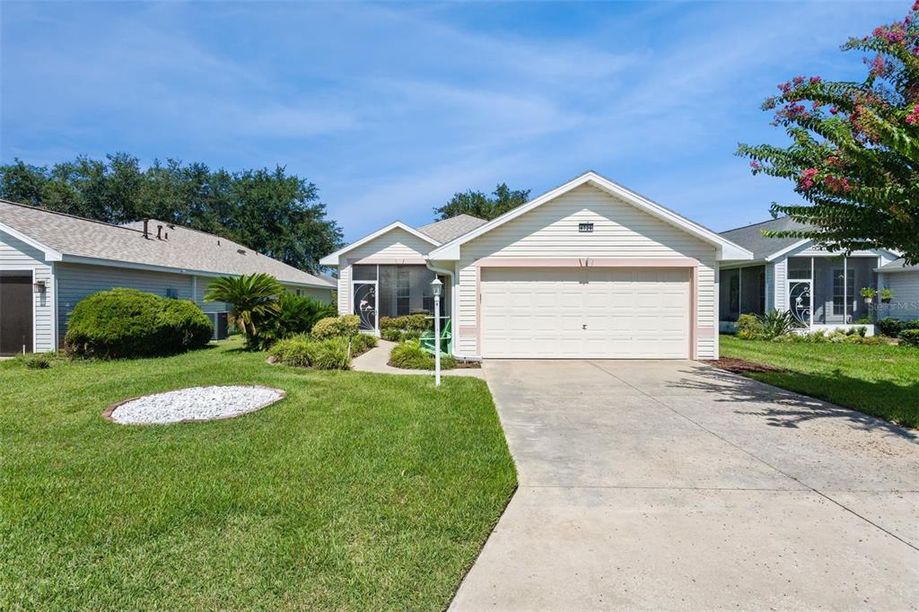 A single-story house with light siding, a two-car garage, and a front lawn — 4726 SAINT ANDREWS ARCADE, LEESBURG, FL
