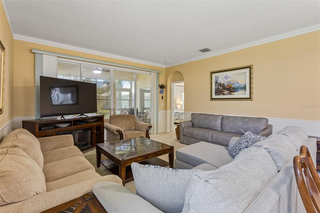 A living room features a beige sofa, a gray sectional, a coffee table, and a television — 4726 SAINT ANDREWS ARCADE, LEESBURG, FL