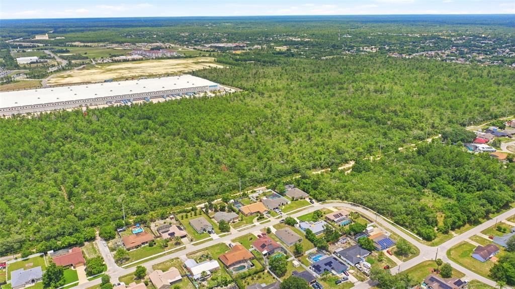 An aerial view shows a residential neighborhood bordering a large expanse of undeveloped forest land — EDGEMONT (PAPER) AVENUE, DELTONA, FL
