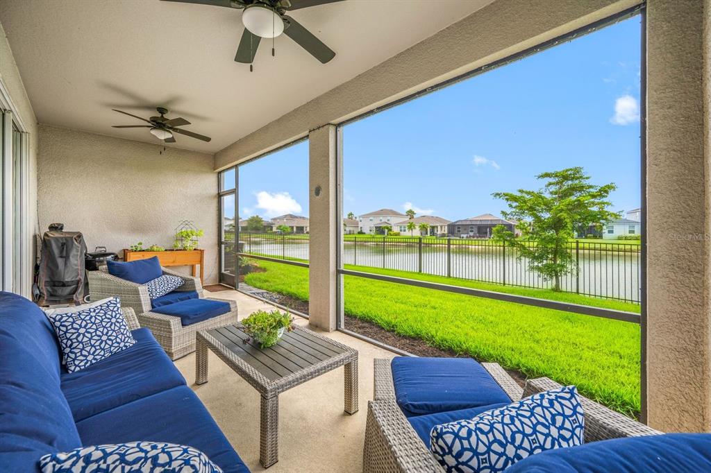 A covered patio with outdoor furniture overlooks a grassy lawn and a lake — 6549 DEVESTA LOOP, PALMETTO, FL