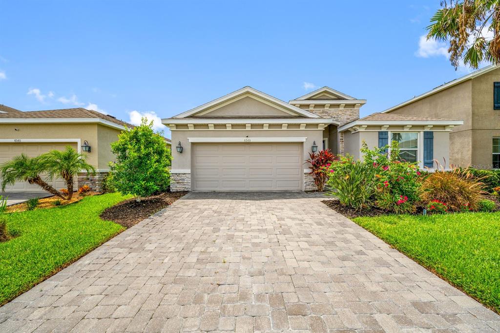 A single-story house with a beige stucco exterior, a paved driveway, and a two-car garage — 6549 DEVESTA LOOP, PALMETTO, FL