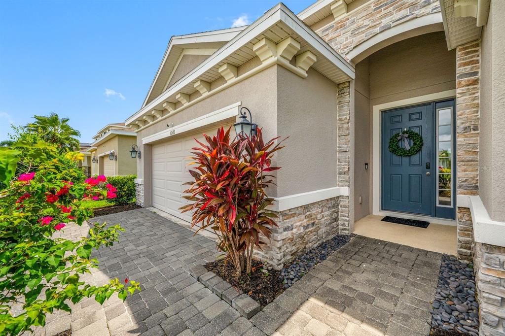 A house exterior featuring a blue front door, stone accents, and a paved driveway — 6549 DEVESTA LOOP, PALMETTO, FL