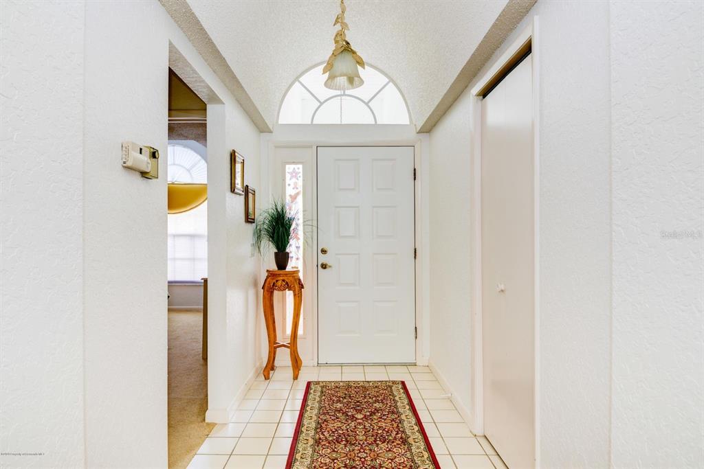 A tiled entryway features a white front door with a sidelight and an arched window — 9408 NEW ORLEANS DRIVE, WEEKI WACHEE, FL