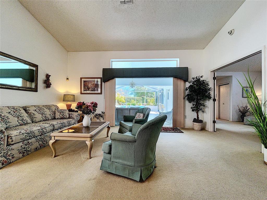 A living room features a floral sofa, two green armchairs, and a sliding glass door — 9408 NEW ORLEANS DRIVE, WEEKI WACHEE, FL