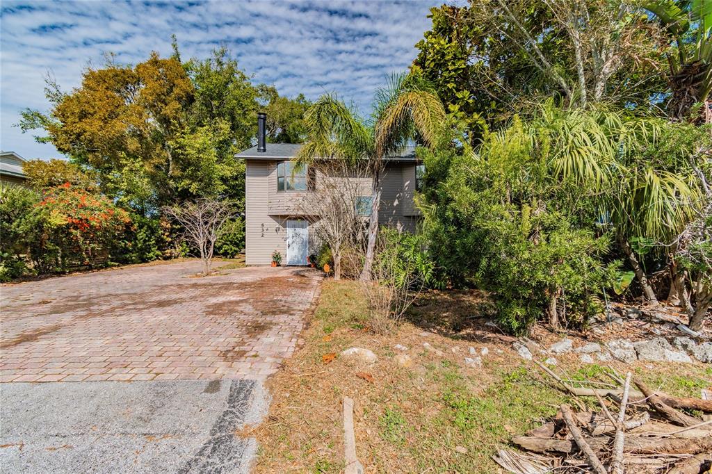 A two-story house with beige siding and a paved driveway sits among lush trees — 532 45TH STREET COURT W, PALMETTO, FL