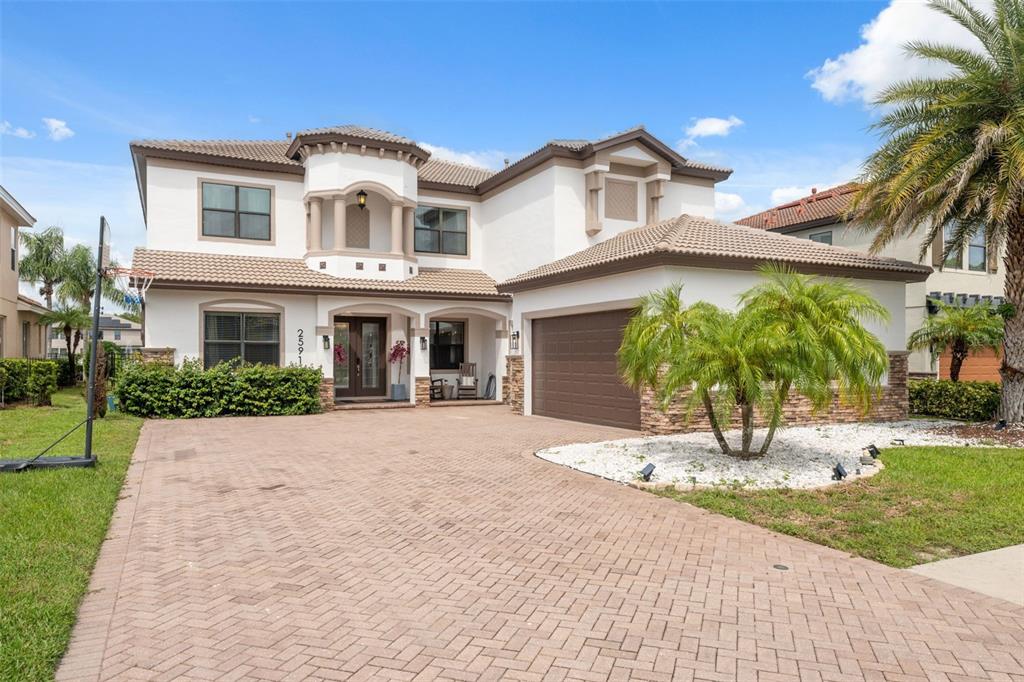 A two-story house with a white stucco exterior, brown roof tiles, and a paved driveway — 2591 GRAND CYPRESS BOULEVARD, PALM HARBOR, FL