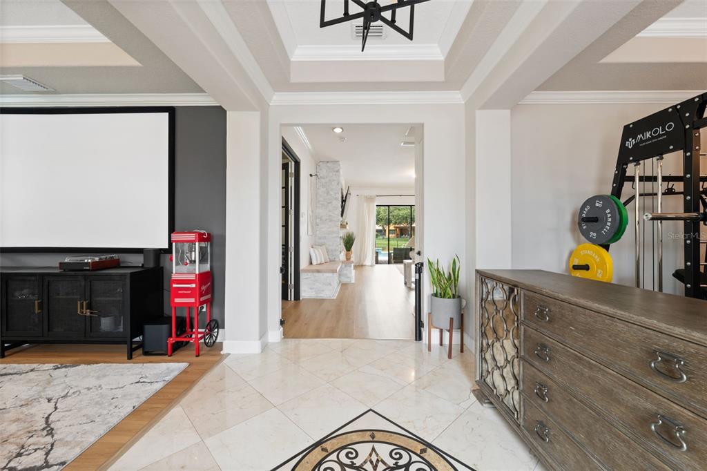 A home theater room with a projector screen, popcorn machine, and gym equipment — 2591 GRAND CYPRESS BOULEVARD, PALM HARBOR, FL