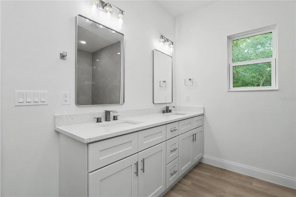 A bathroom features a double vanity with white cabinets, quartz countertops, and two rectangular mirrors — 16503 SW 31ST TERRACE, OCALA, FL